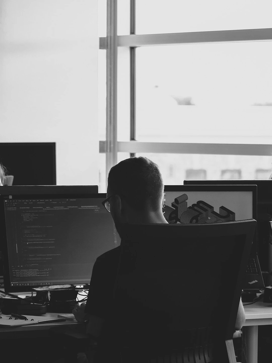 Four people around a table in a bright office, looking over work on a tablet